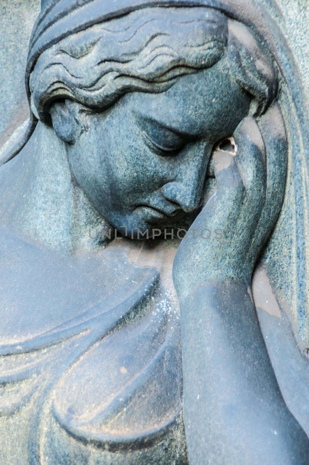 detail of a mourning sculpture on a cemetery