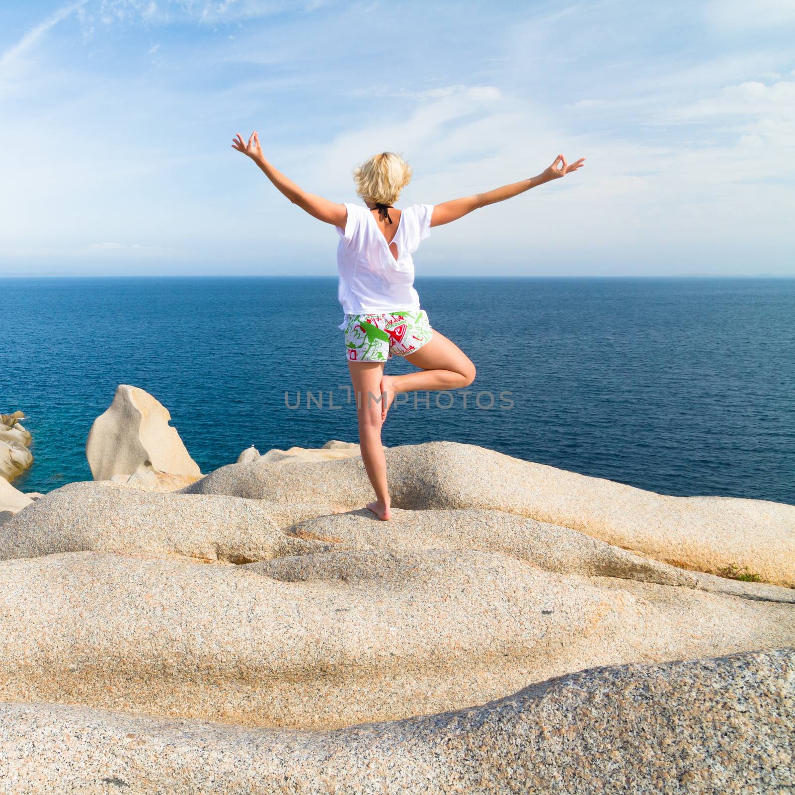 Woman practicing yoga at the beach. by kasto