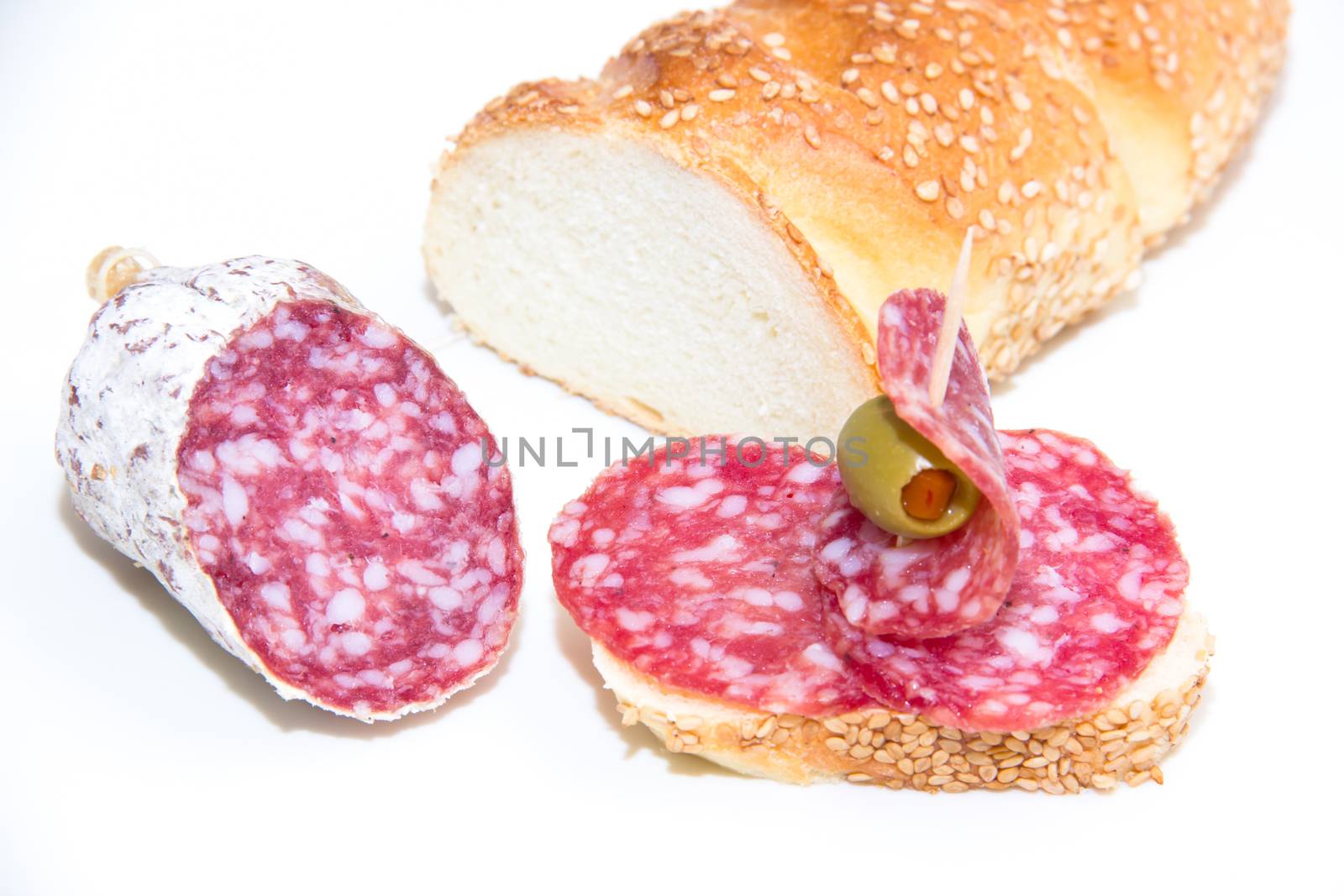 Bread with slices of salami on white background