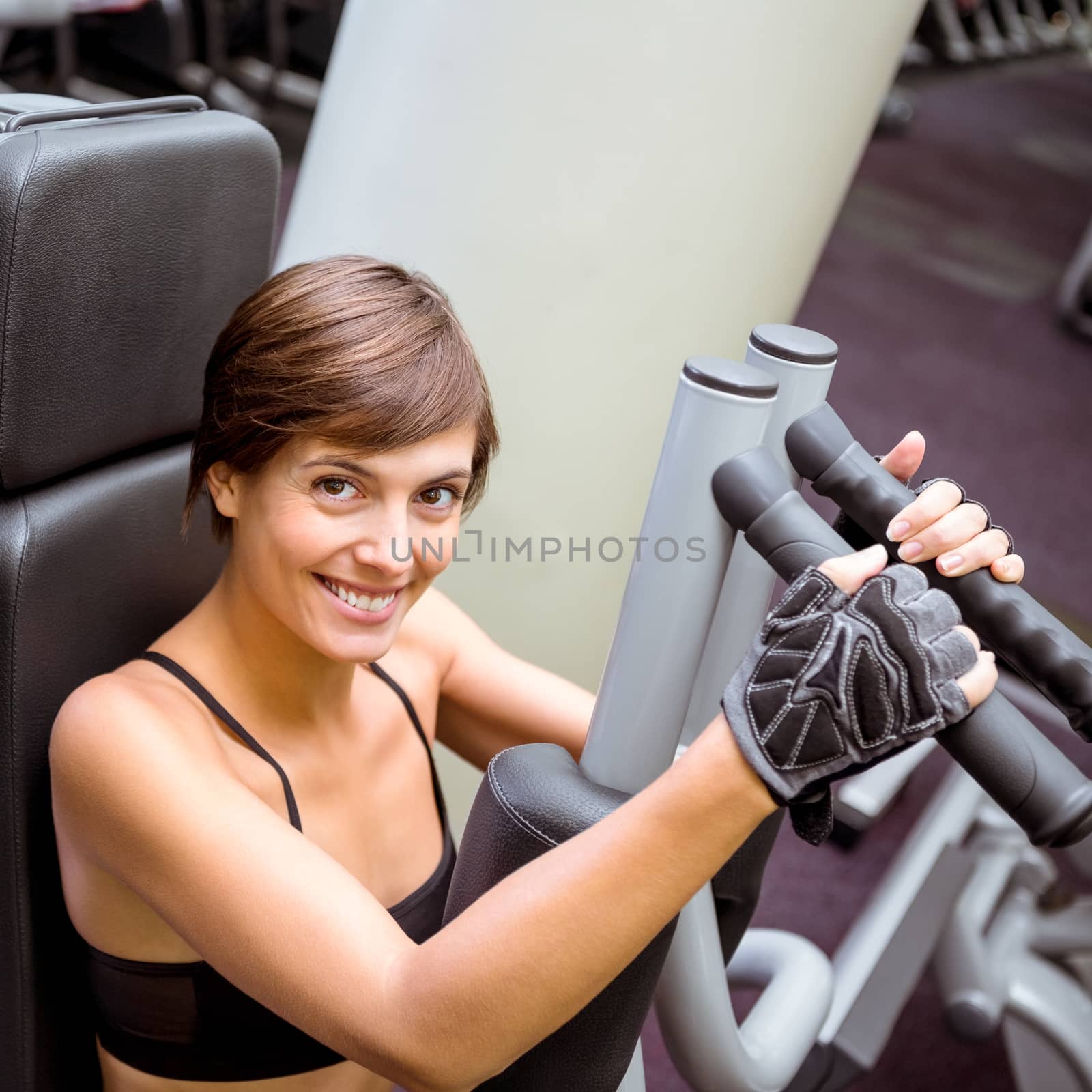 Focused brunette using weights machine for arms by Wavebreakmedia