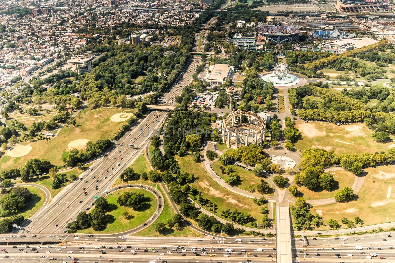 Aerial view of the Borough of Queens, New York, showing densely packed buildings and a multi-lane super highway