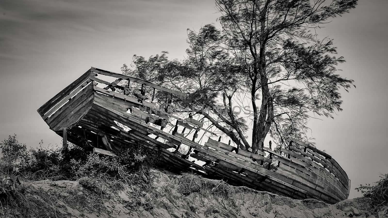 An old wooden boat washed ashore and left abandoned on mound by the Maputo Bay beach