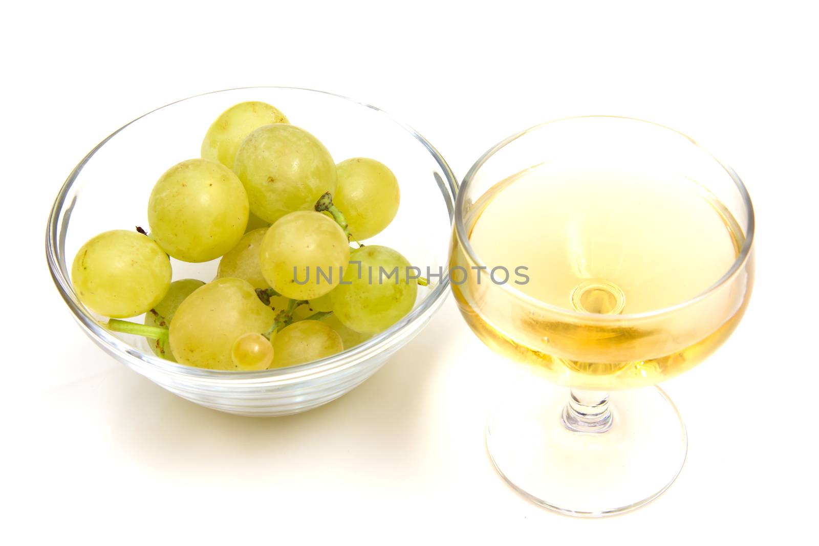 Glass of wine and grapes on bowl on white background