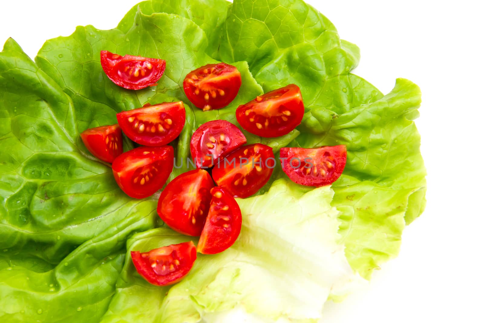 Cherry tomatoes on lettuce on white background close up
