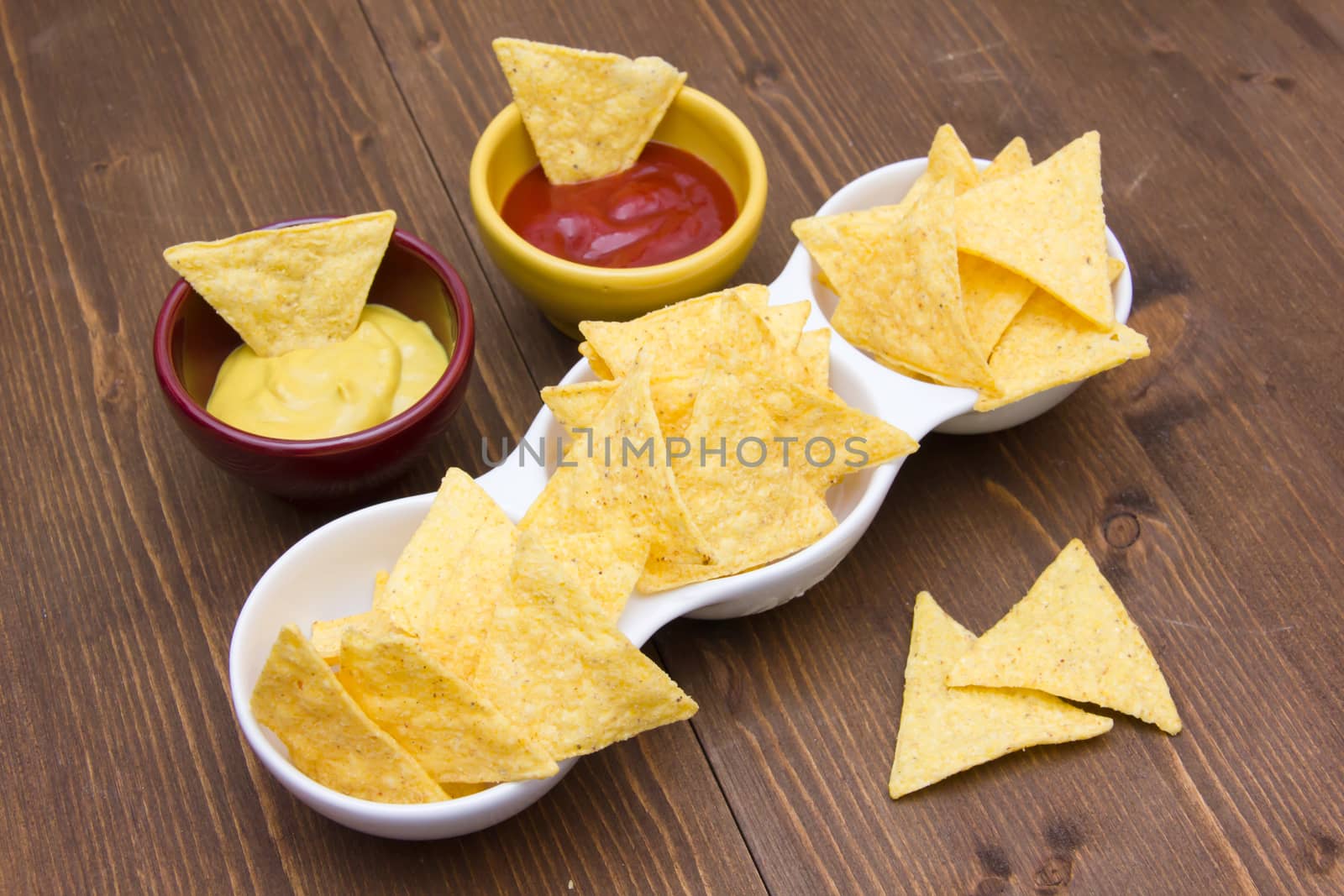 Nachos with sauces on wooden table