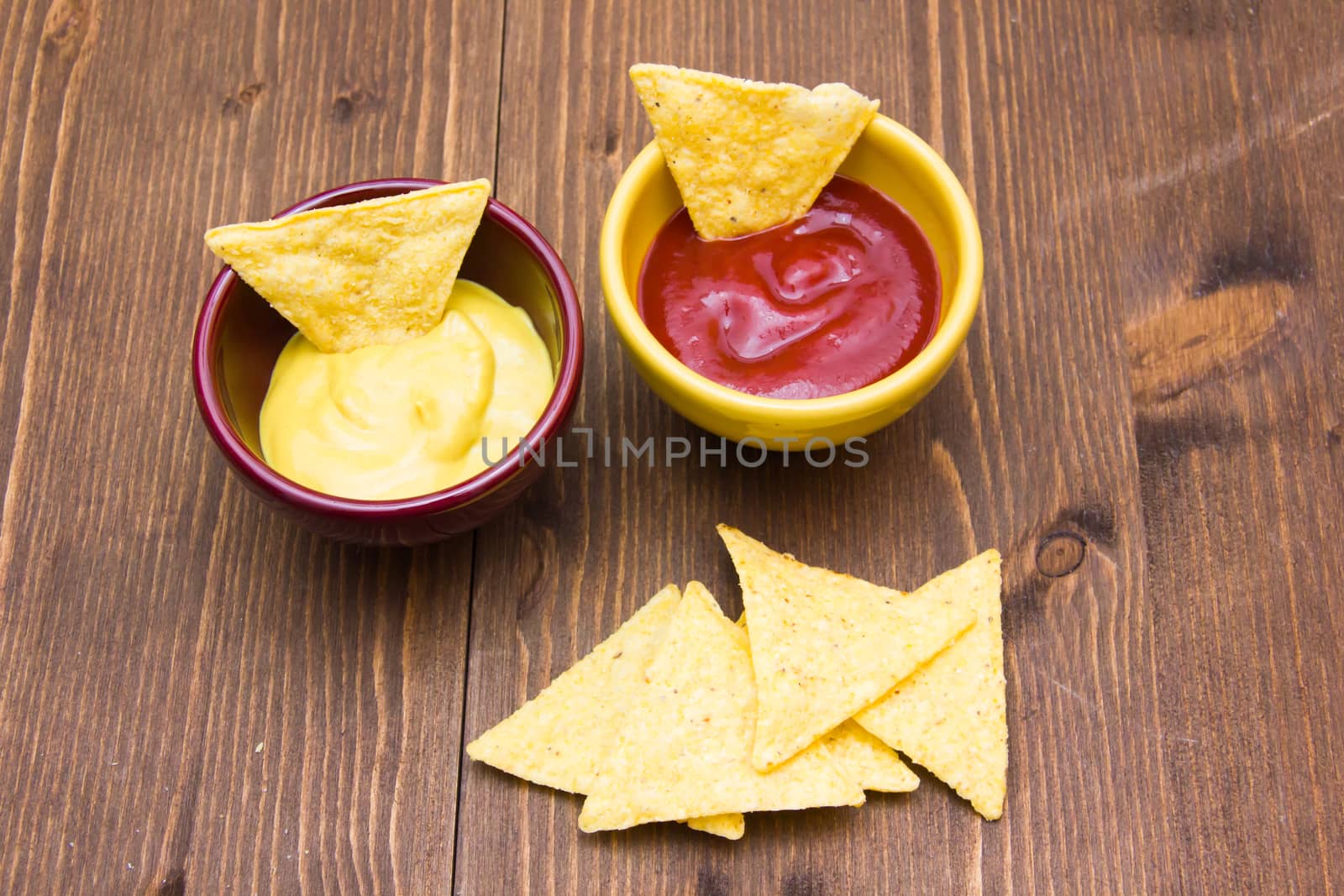 Nachos on wooden table with sauces