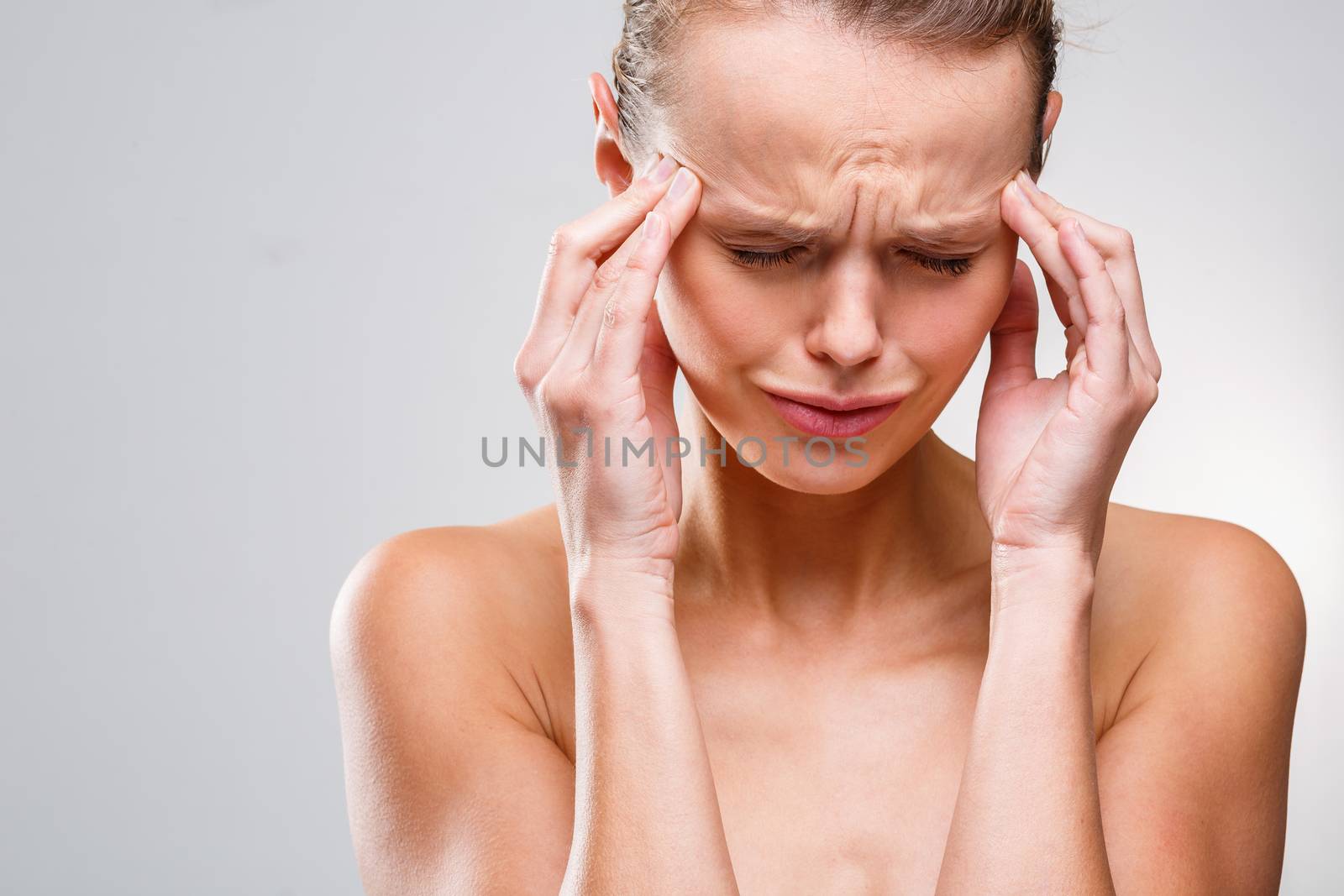 Beautiful woman suffering from acute headache over grey clean background