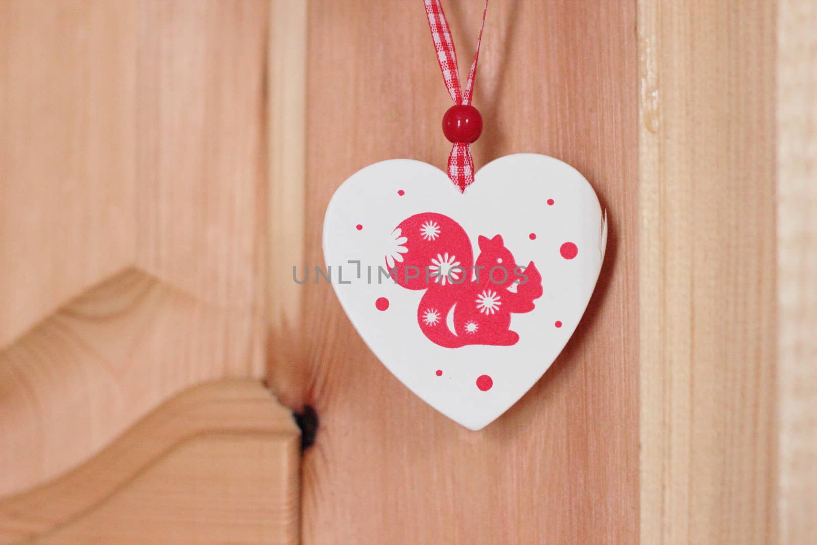 Christmas toy squirrel in the heart. Wood on a red ribbon