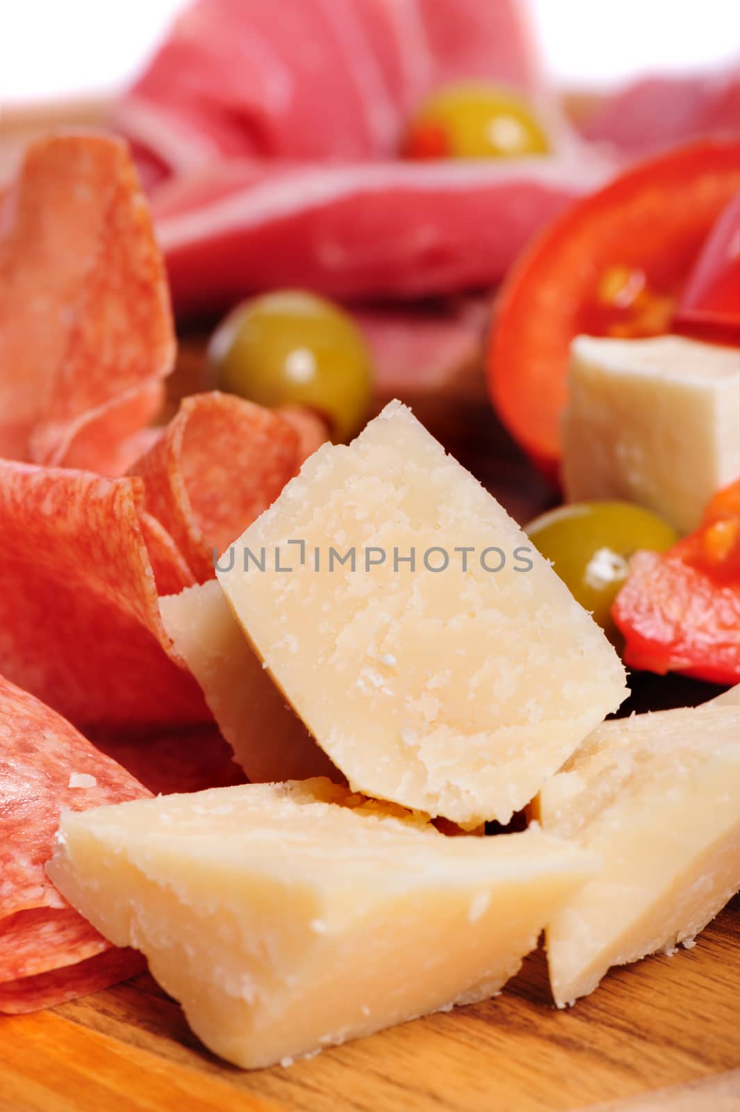 Wooden tray with fresh vegetables, olives, prosciutto and parmiggiano