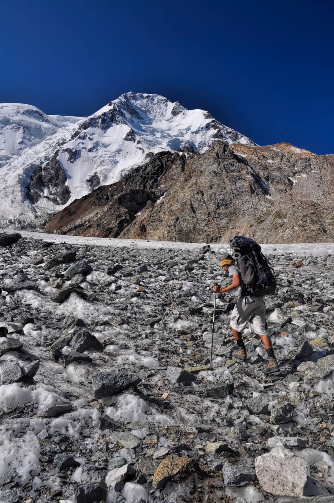 Hiker with backpack on glacier below highest peaks in Tien-Shan mountain range in Kyrgyzstan