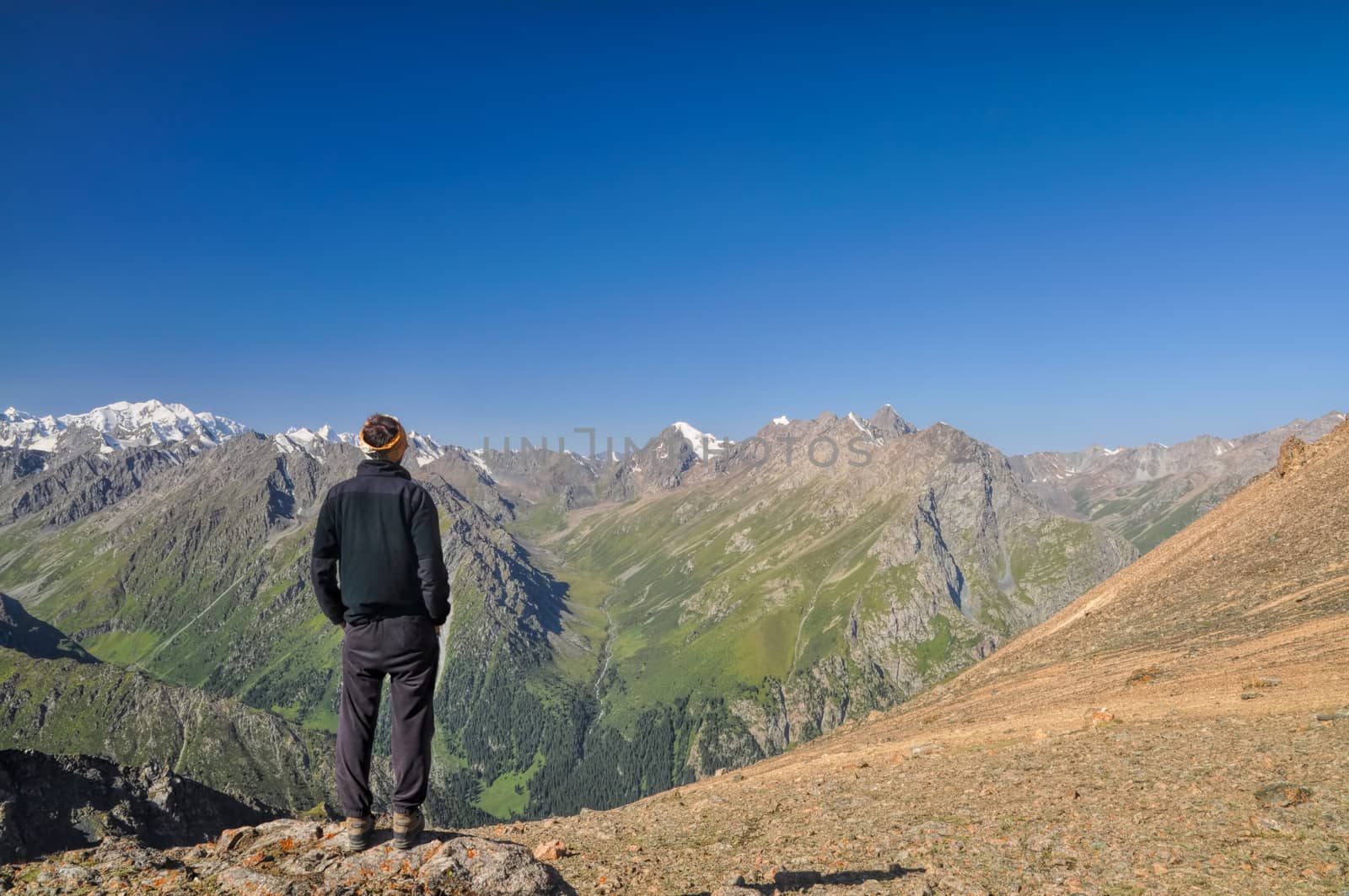 Hiker looking at view of Tien-Shan mountain range in Kyrgyzstan