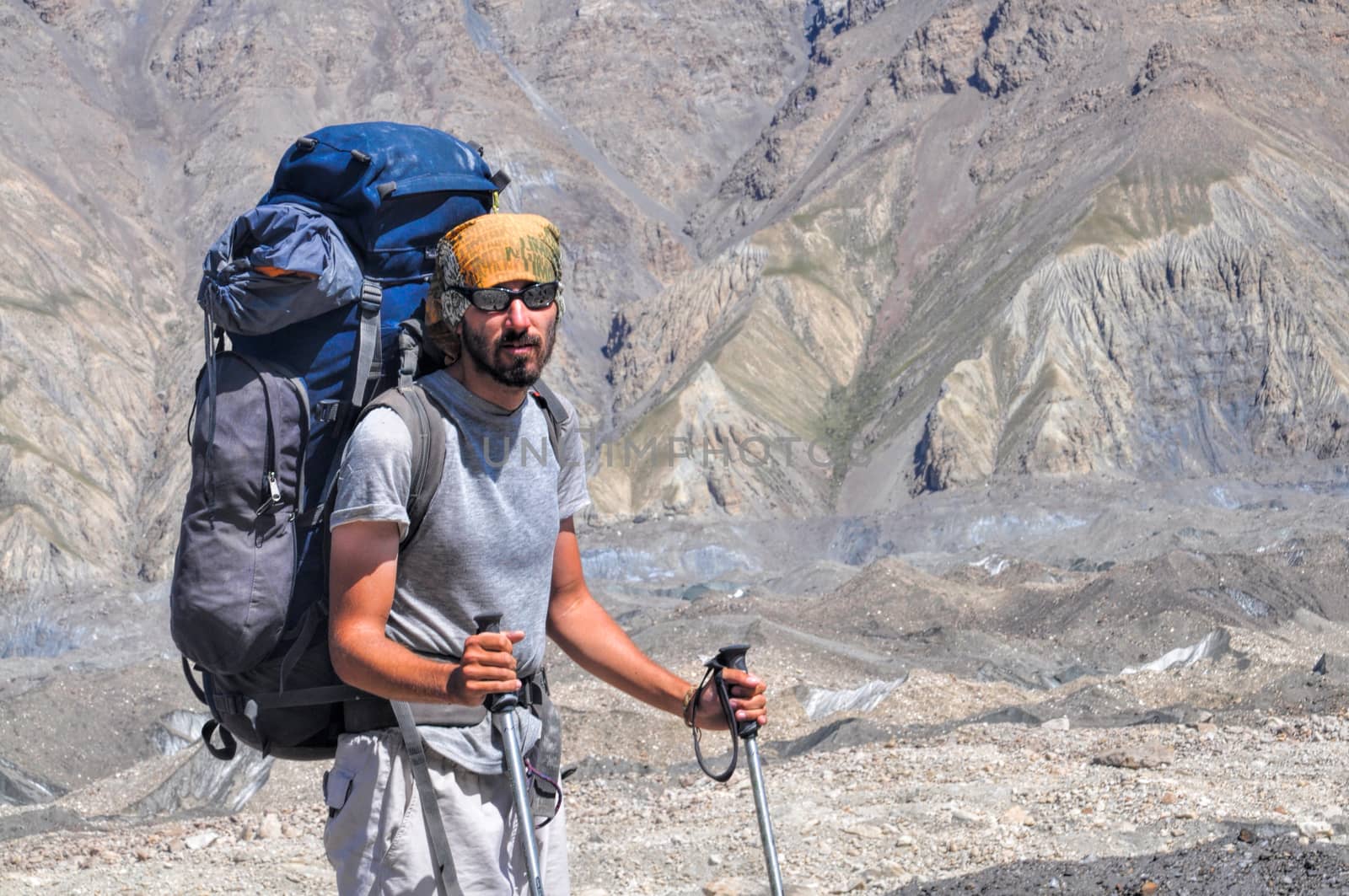 Hiker with large backpack on Engilchek glacier with scenic Tian Shan mountain range in Kyrgyzstan