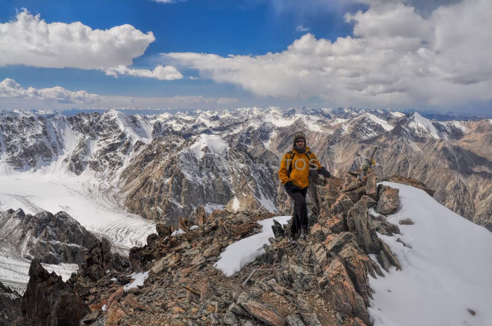 Adventurous young hiker on mountain summit in scenic Tian Shan range in Kyrgyzstan, Ala Archa national park