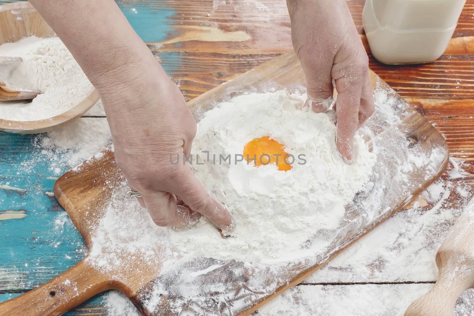 Hands kneading dough on board - flour and eggs