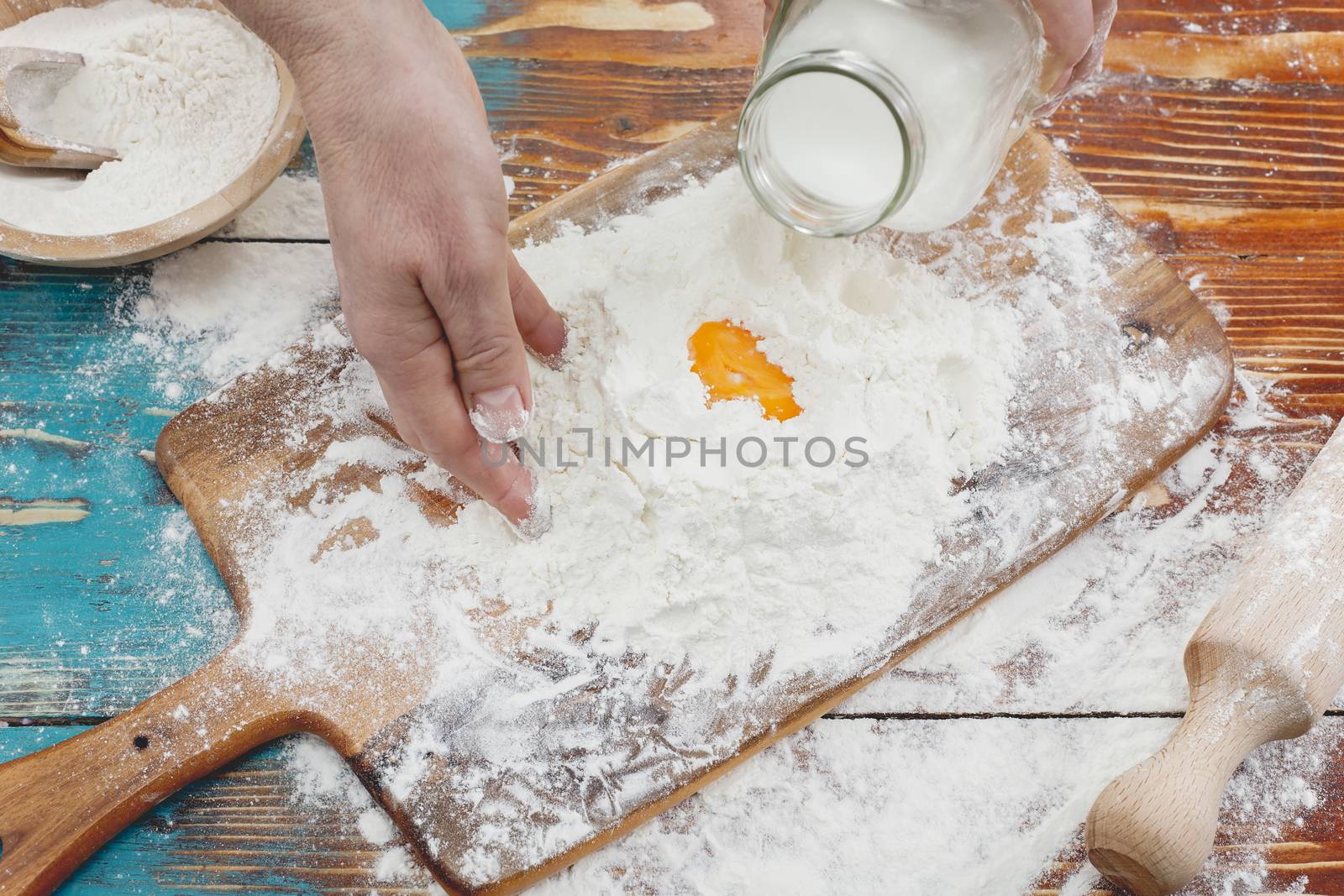 Woman pouring milk into flour as she prepares to bake