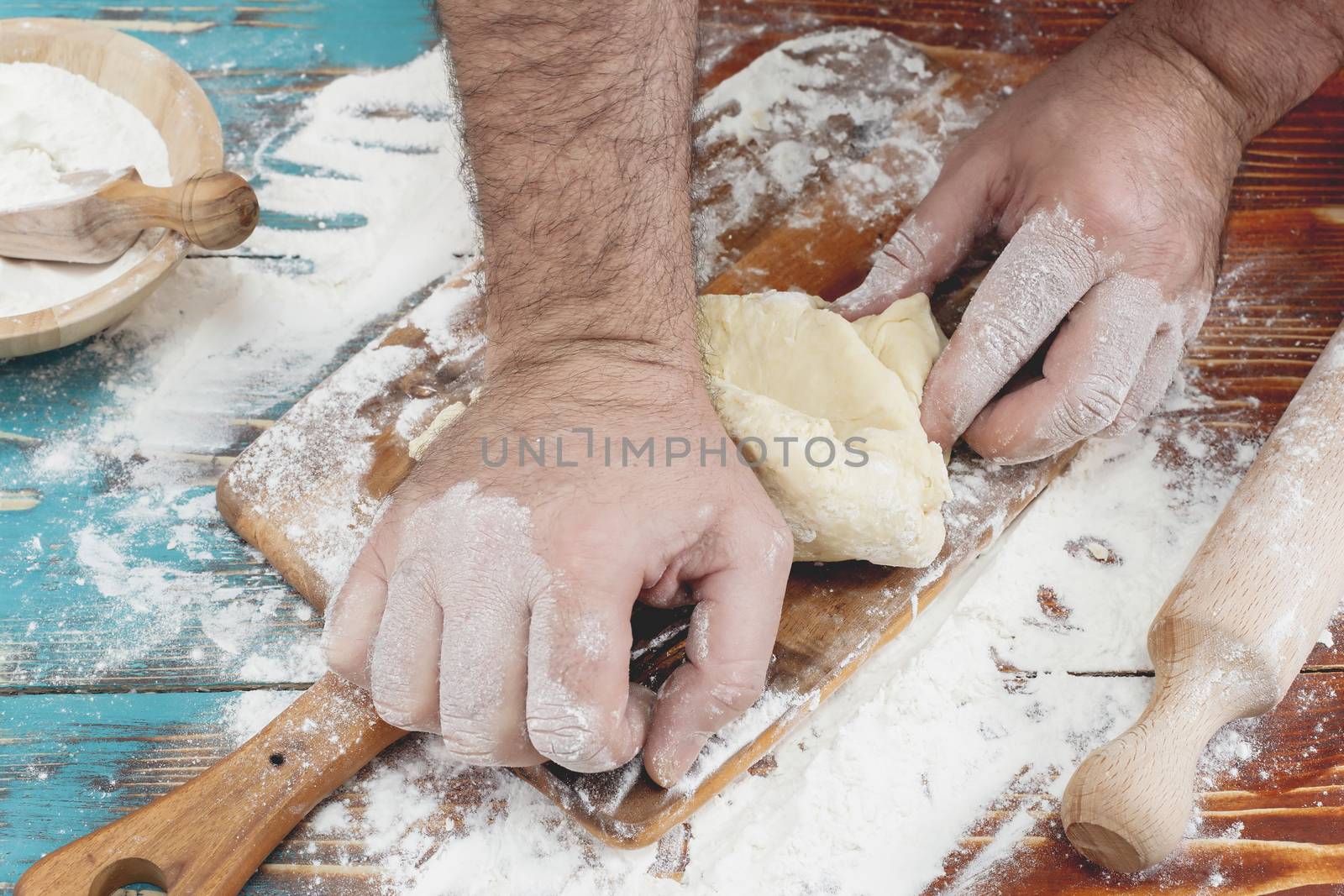 Hands of a man kneading dough for home made pizza
