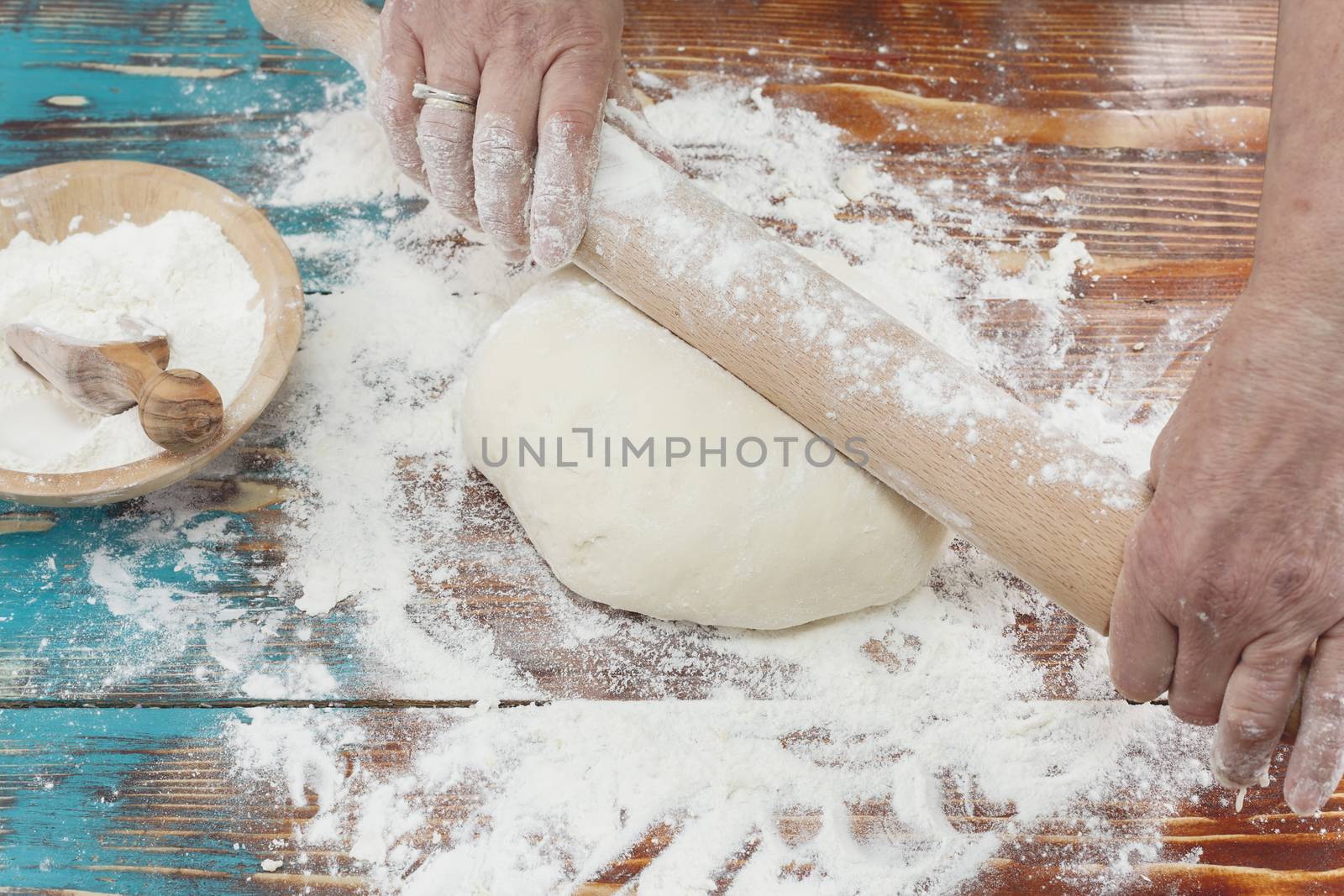 Woman rolling dough with rolling pin on kitchen counter