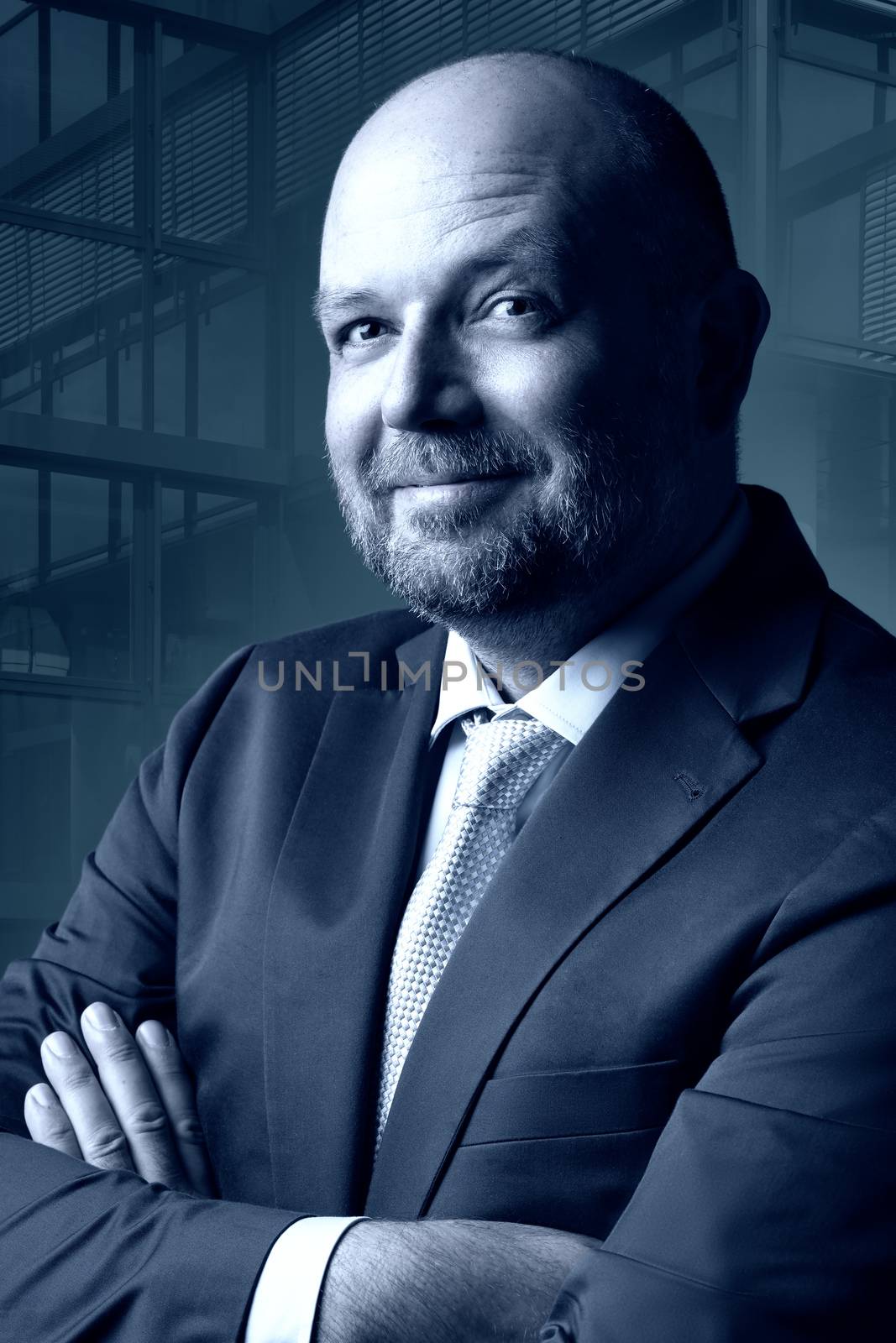 Thoughtful businessman in dark suit and tie in front of blue background