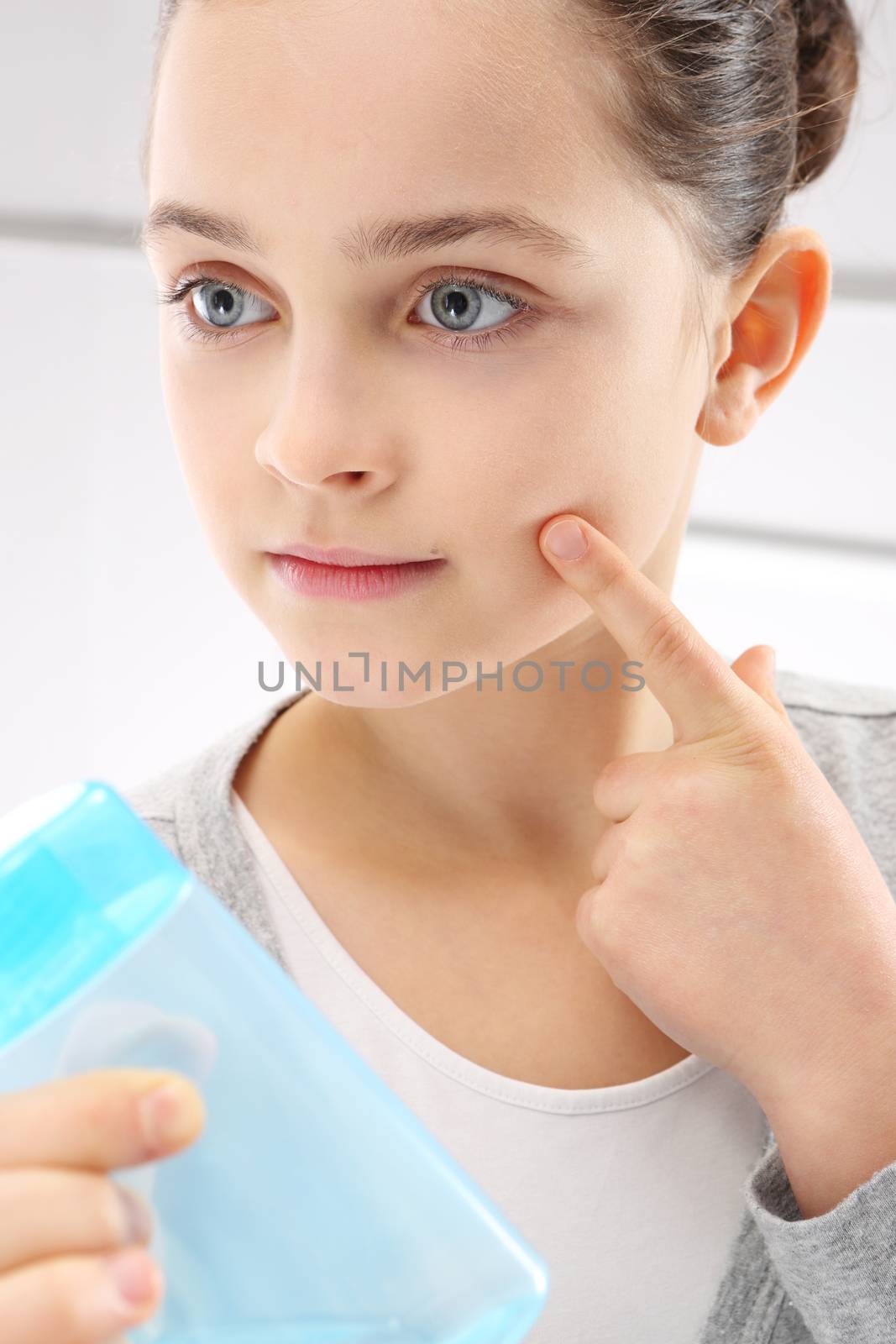 Beautiful a young teenager cleanses the facial skin tonic