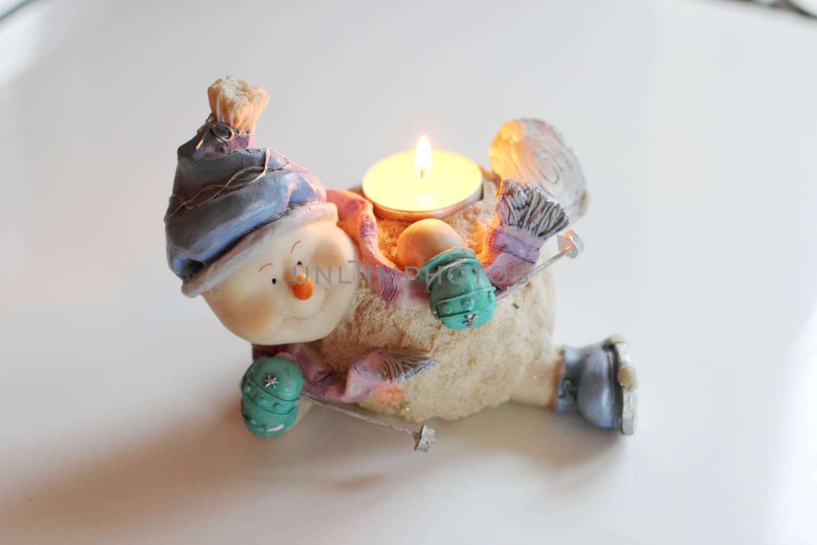 Cheerful snowman skier. Candlestick with burning candle