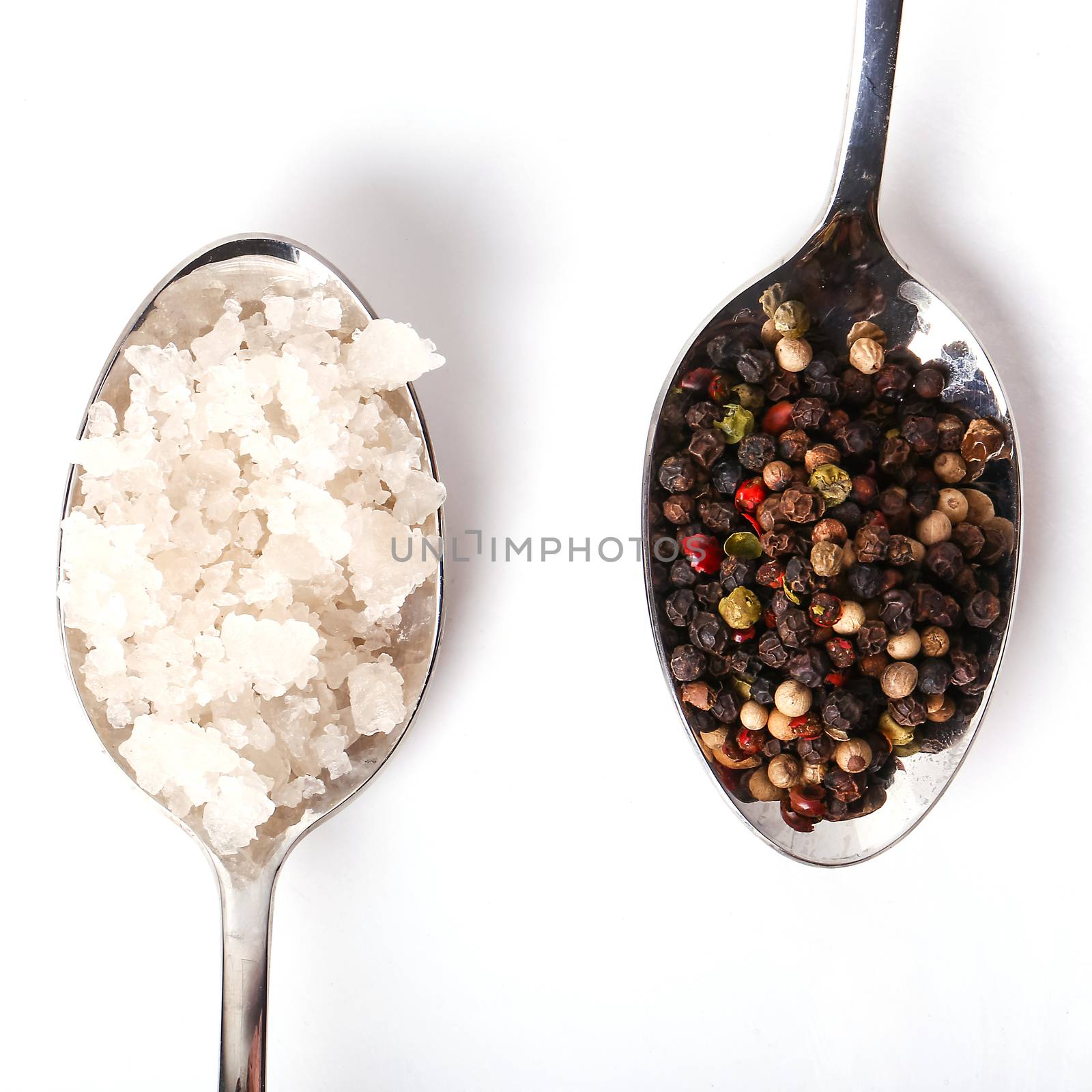 Heap of sea salt and peppercorn on a white background
