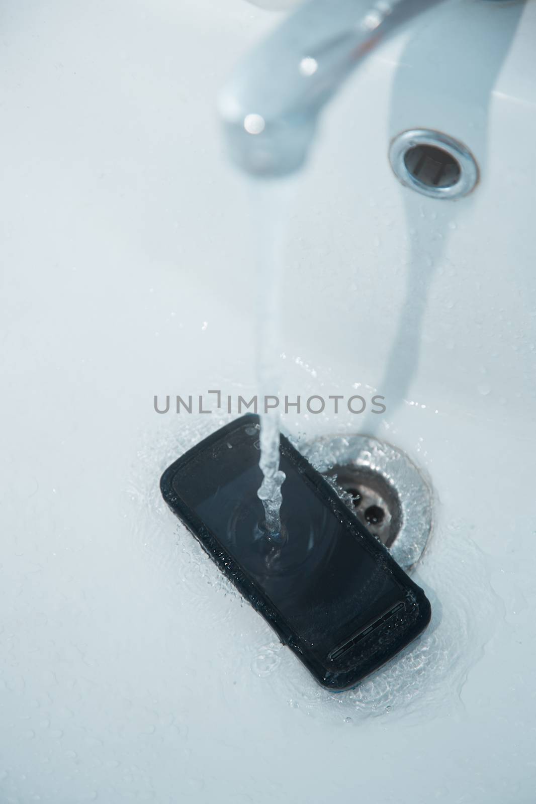 Smartphone in sink with flowing water by Novic