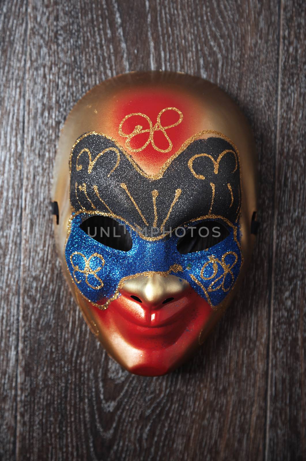 Carnival Venetian mask on a hardwood wall. Vertical photo