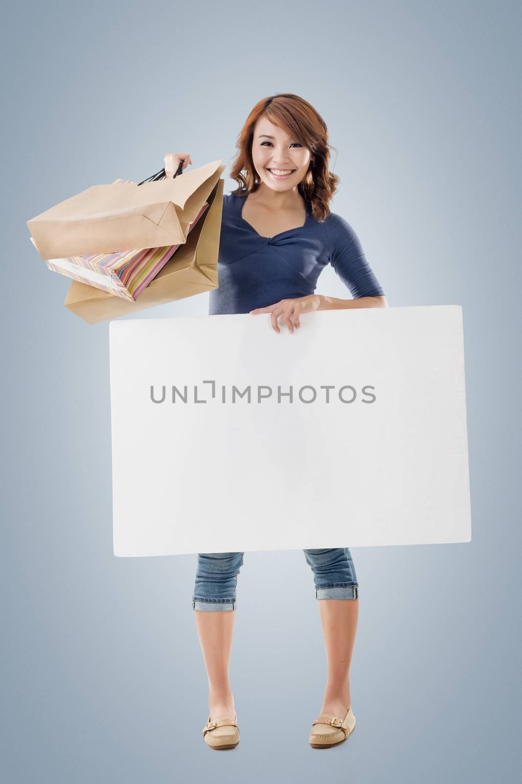 Shopping woman holding bags and blank board, full length portrait isolated.
