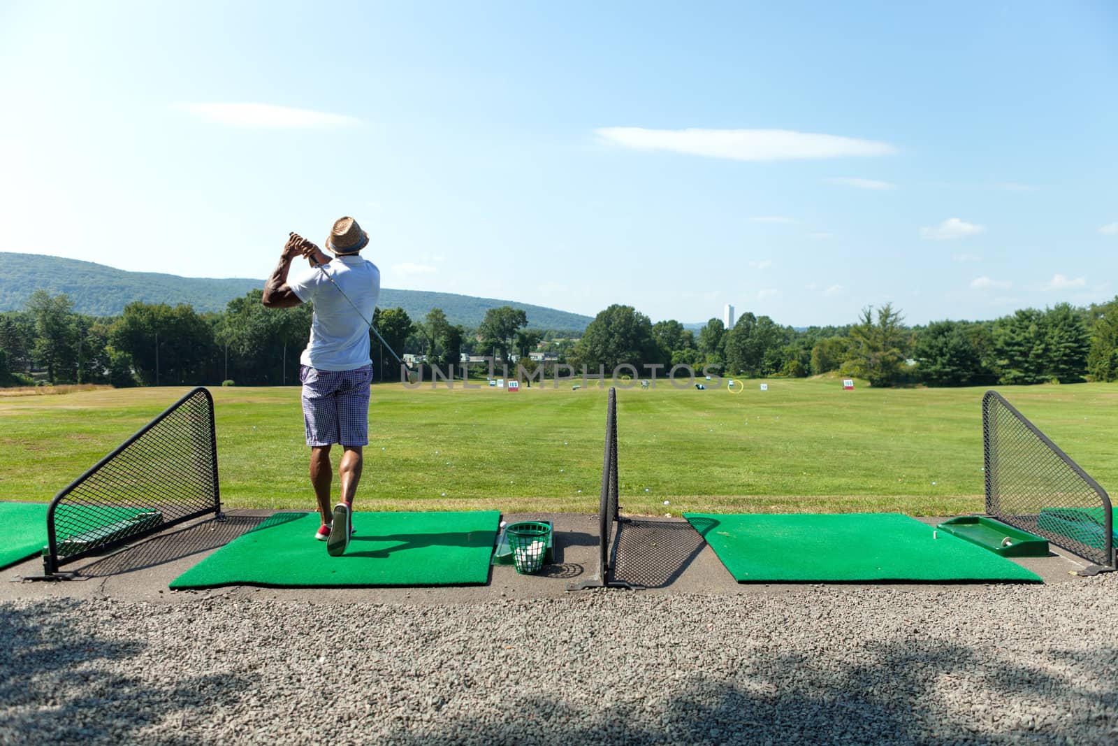 Athletic golfer swinging at the driving range dressed in casual attire.