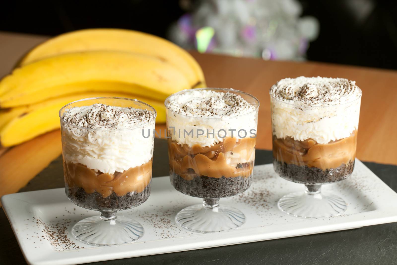 Banana caramel parfait desserts with fresh whipped cream and chocolate cookie crumbles.