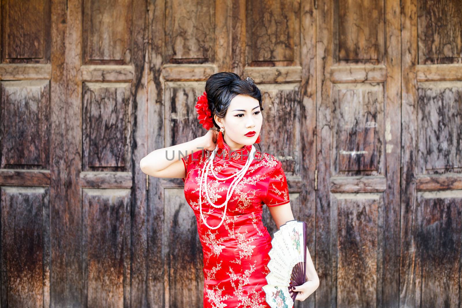 Chinese woman red dress traditional cheongsam ,close up portrait with old wood door