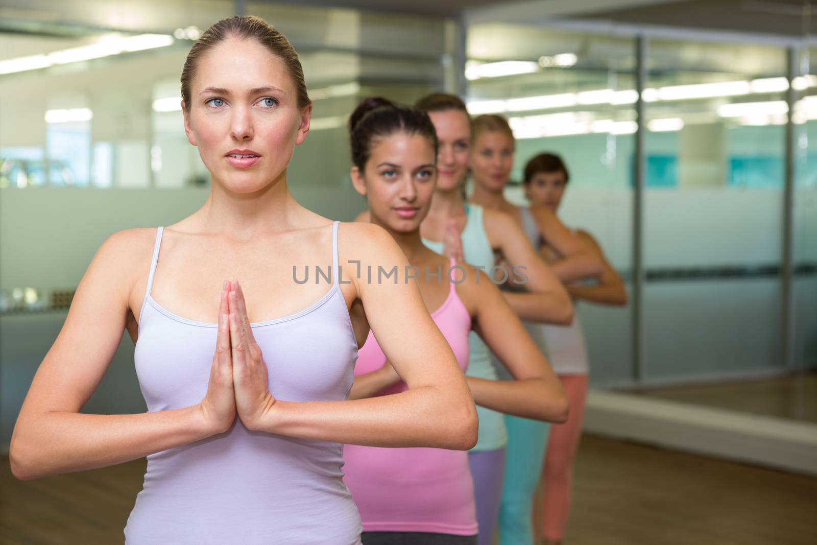 Yoga class in tree pose in fitness studio at the gym