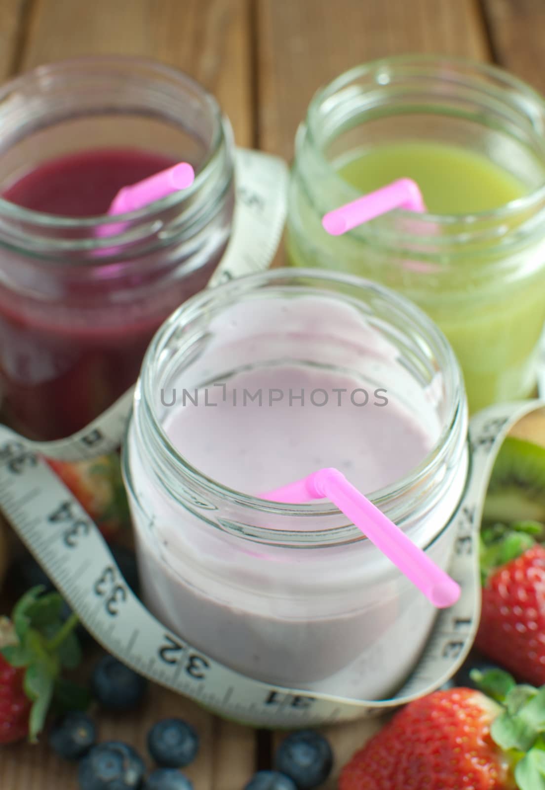 Three flavored smoothies in jars with fruit 