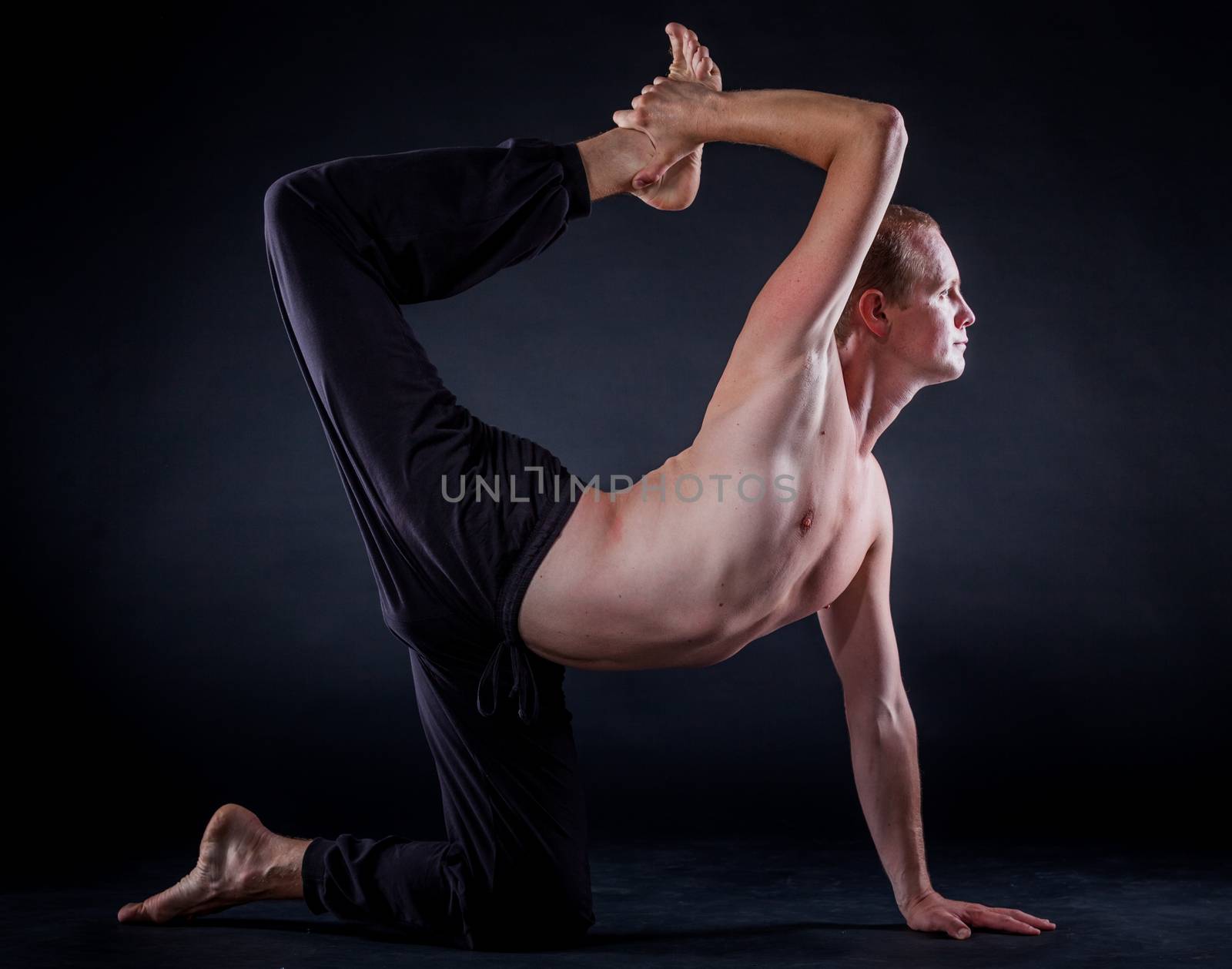 Handsome man doing yoga. Shot on black background