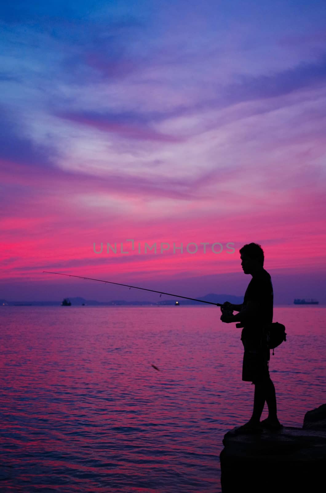 Silhouette of man fishing beside the sea by pixbox77