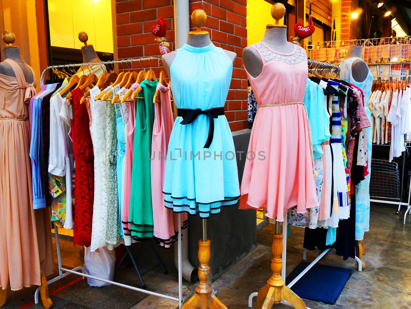 Clothing store hanging clothes women, beautiful colors located in front of the shop.                           