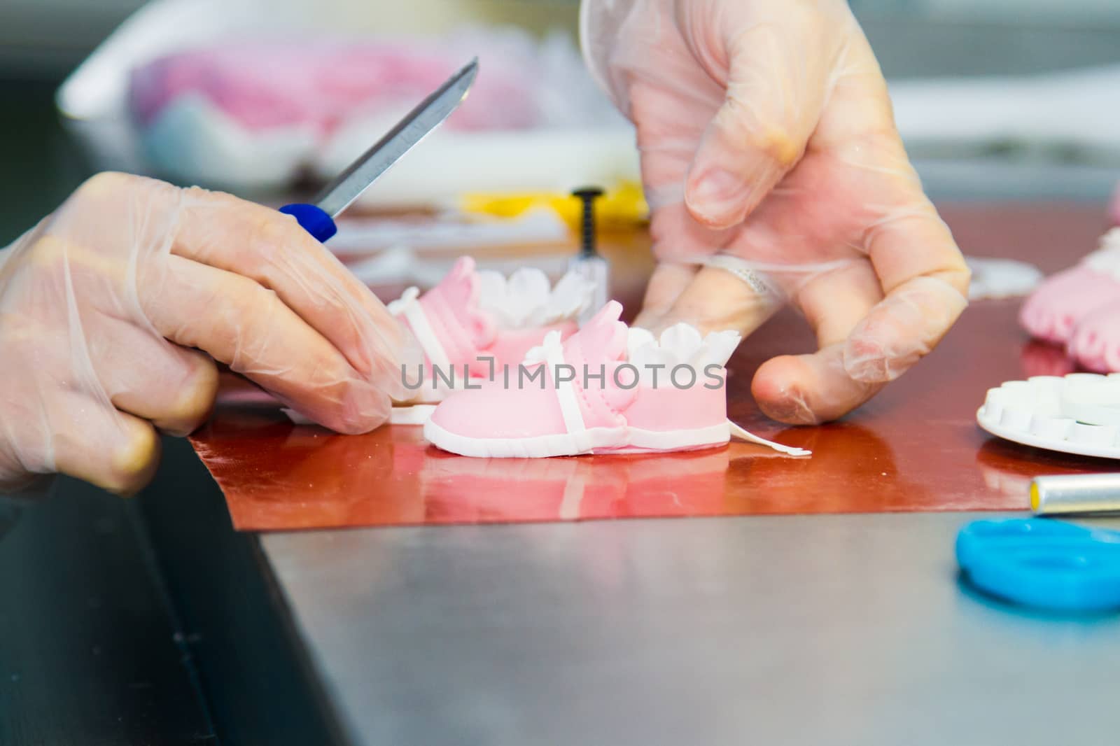 The chef prepares a decoration for the cake in the form of pink shoes