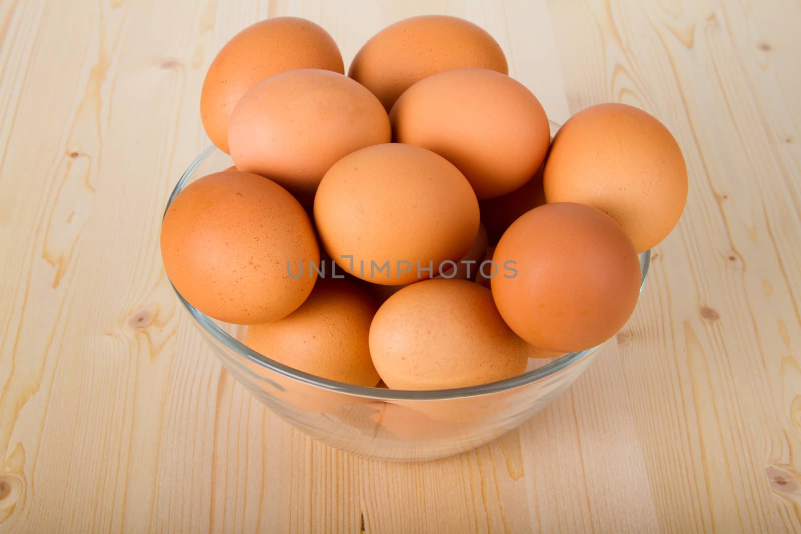 Fresh brown eggs in a bowl on wooden table