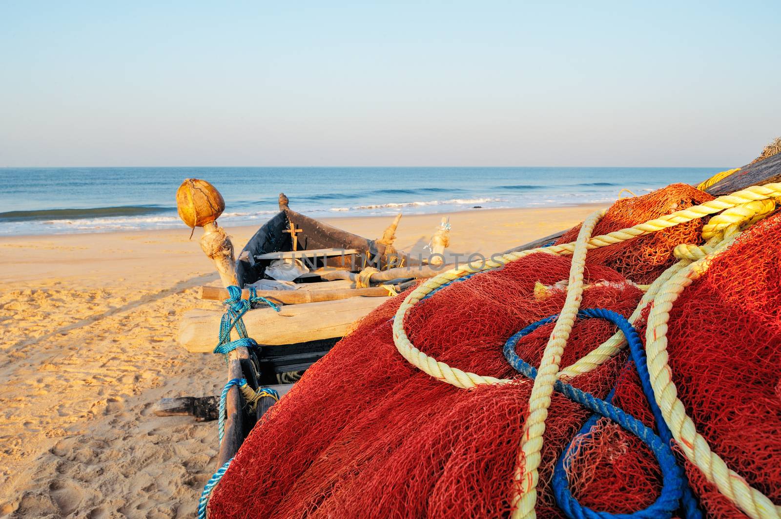 Old fishing boat with red net on the shore of Goa, India