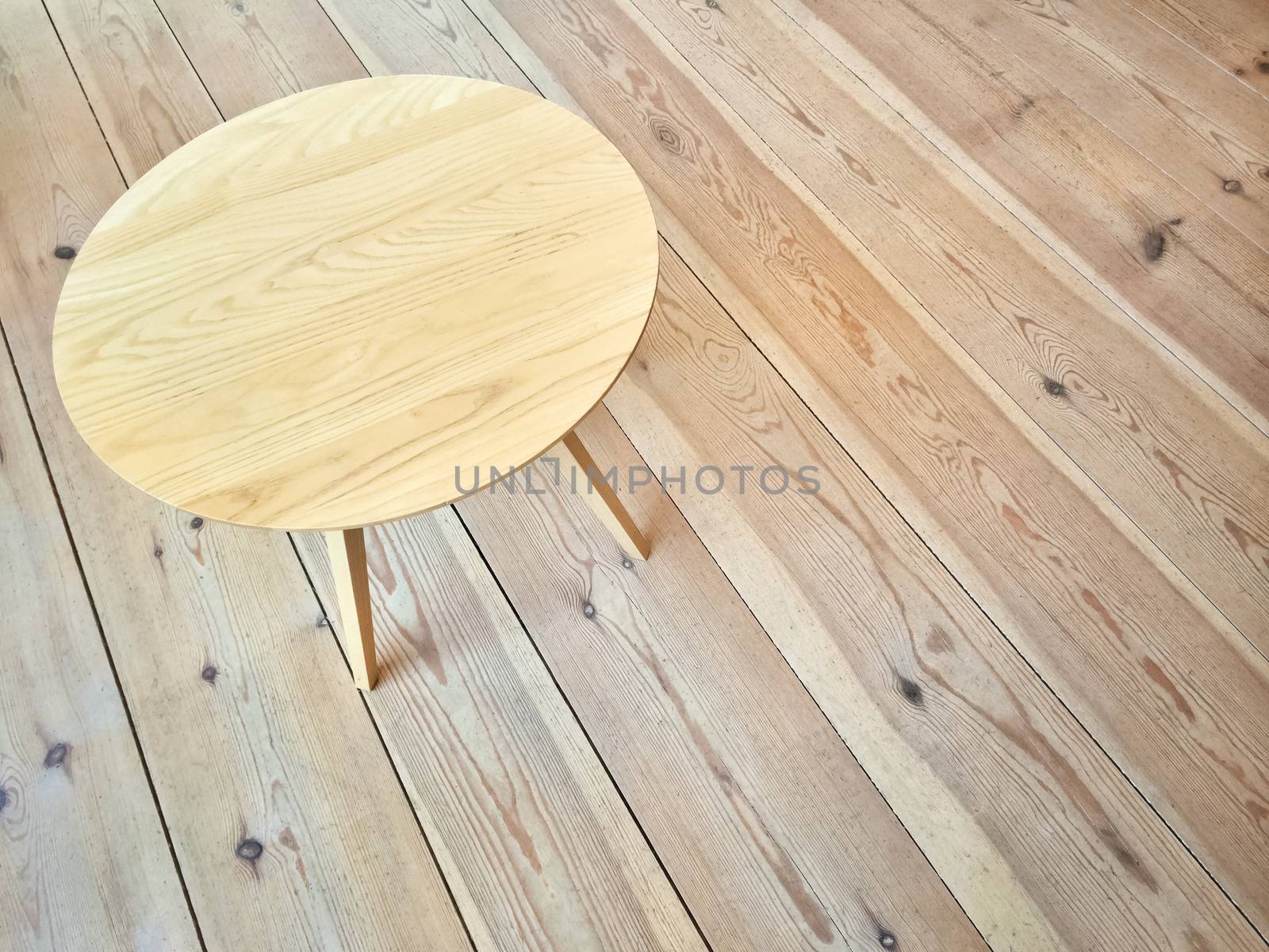 Simple round table on wooden floor by anikasalsera