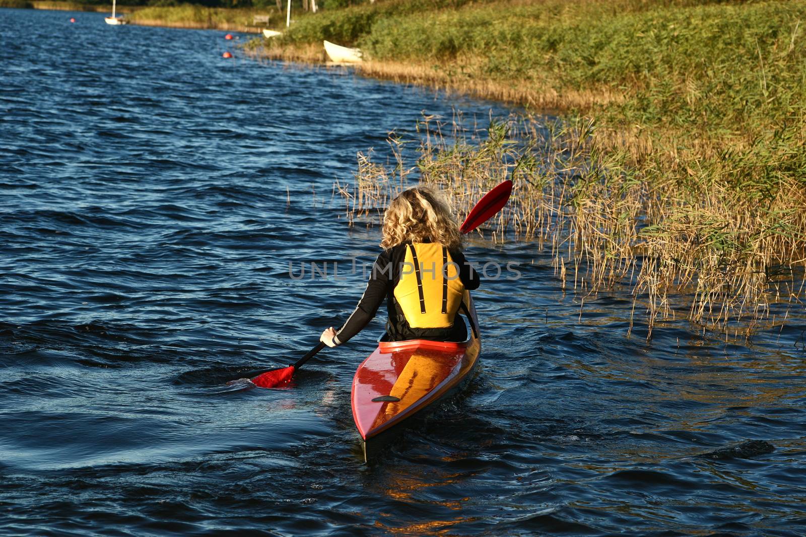 Blond girl on a kayak on a lake in Denmark