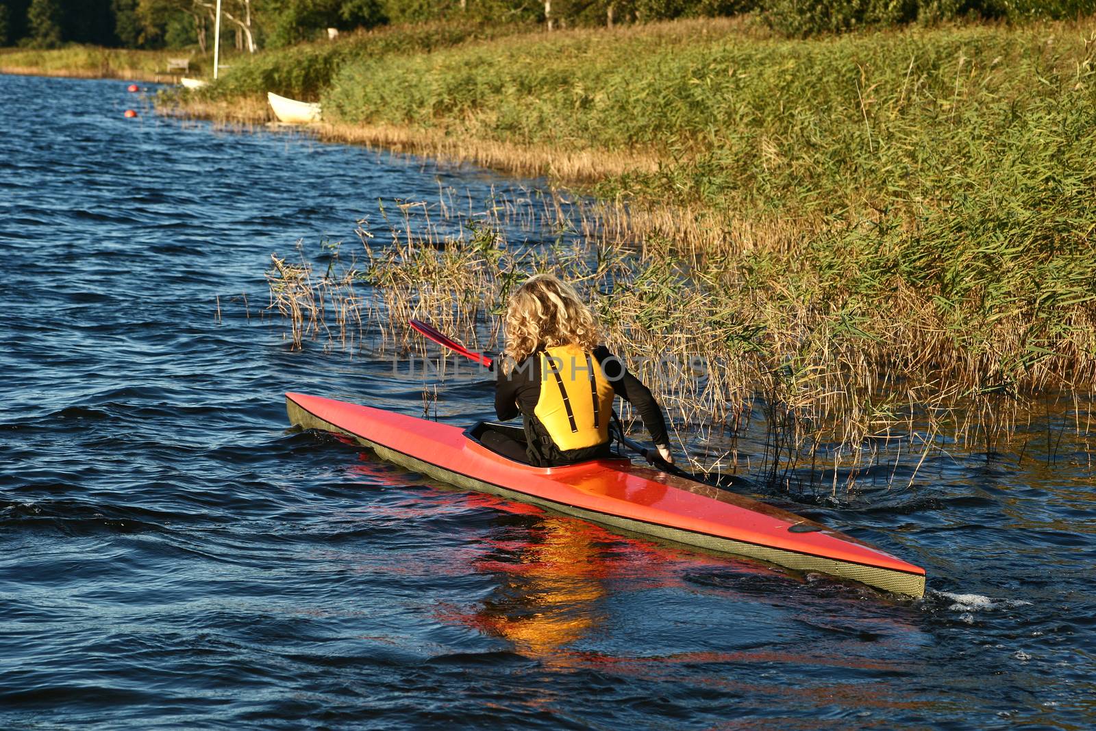 Blond girl on a kayak on a lake in Denmark