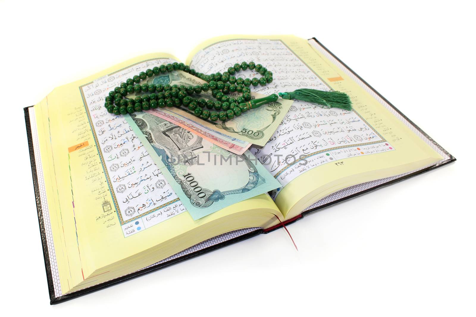 Koran with Afghan banknotes in front of white background