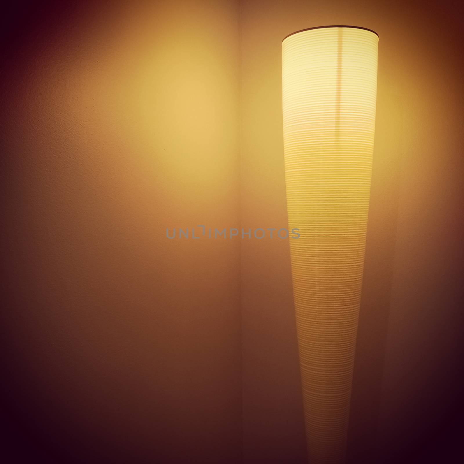 Modern lamp illuminating a dark room corner.