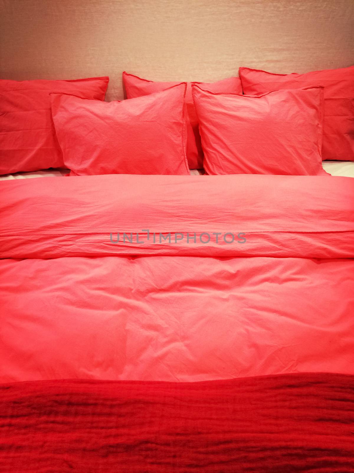 Bed with lots of pillows and red romantic bed linen.