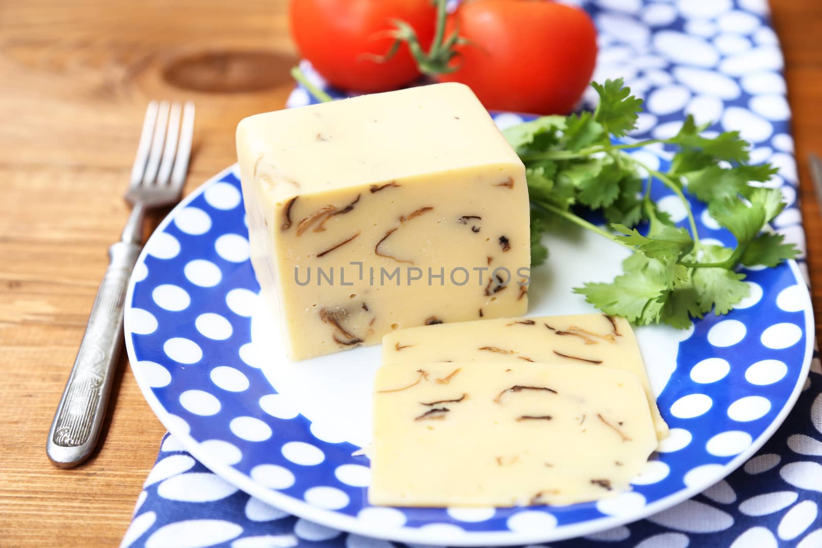 cheese with mushrooms,near the red tomatoes on wooden plate