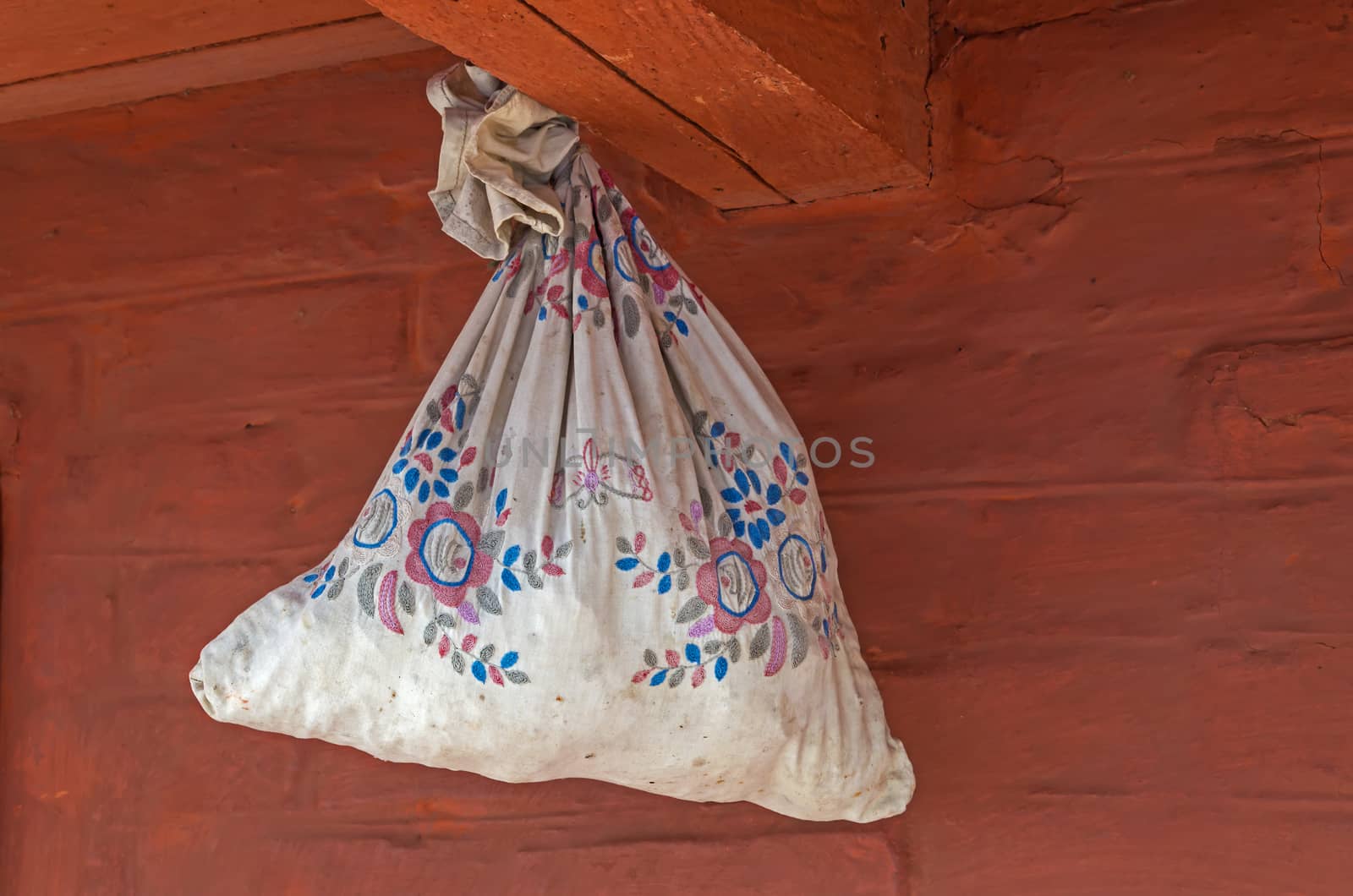 A feedbag with seeds hanging under the roof of a village house.