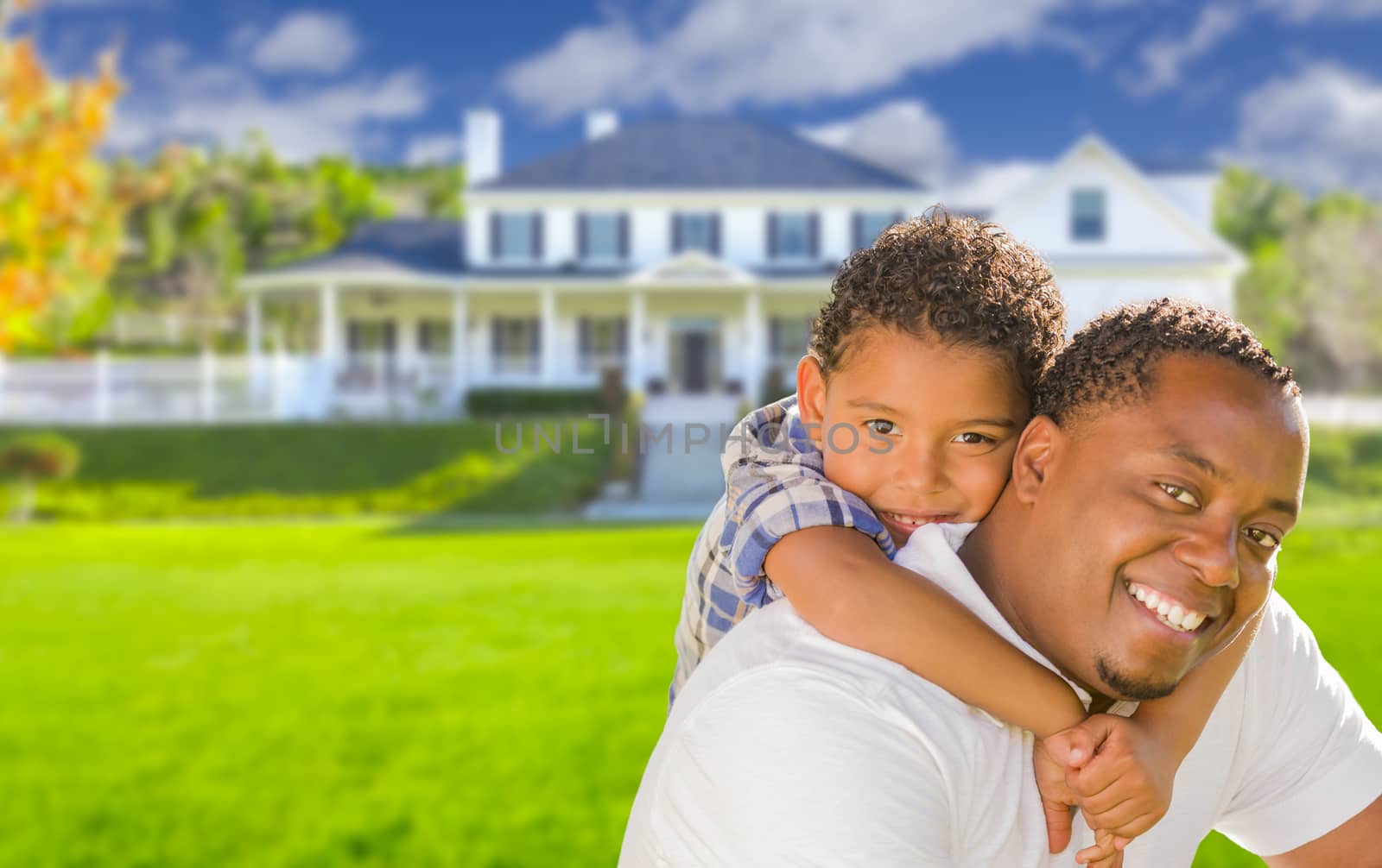 Happy Playful African American Father and Mixed Race Son In Front of House.