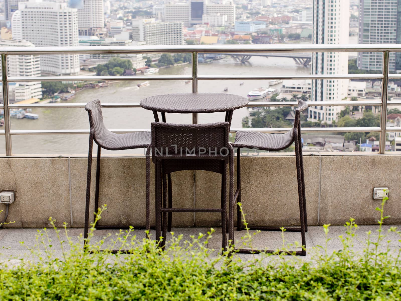 Rattan oone table with two stool chairs standing against the terrace