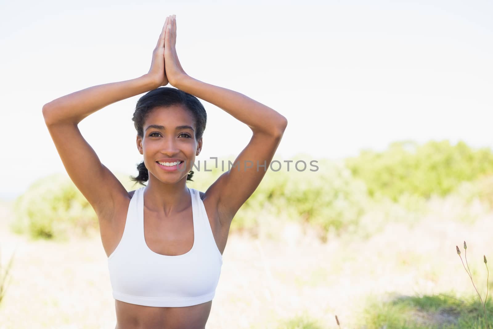 Fit woman sitting on grass in lotus pose smiling at camera by Wavebreakmedia
